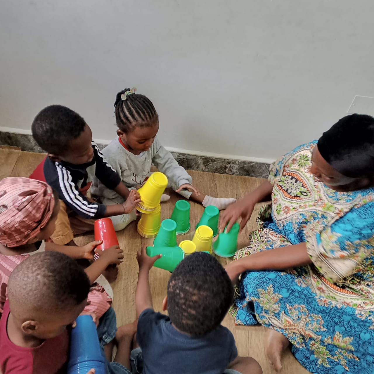Teacher leading a cup-stacking game with children after school