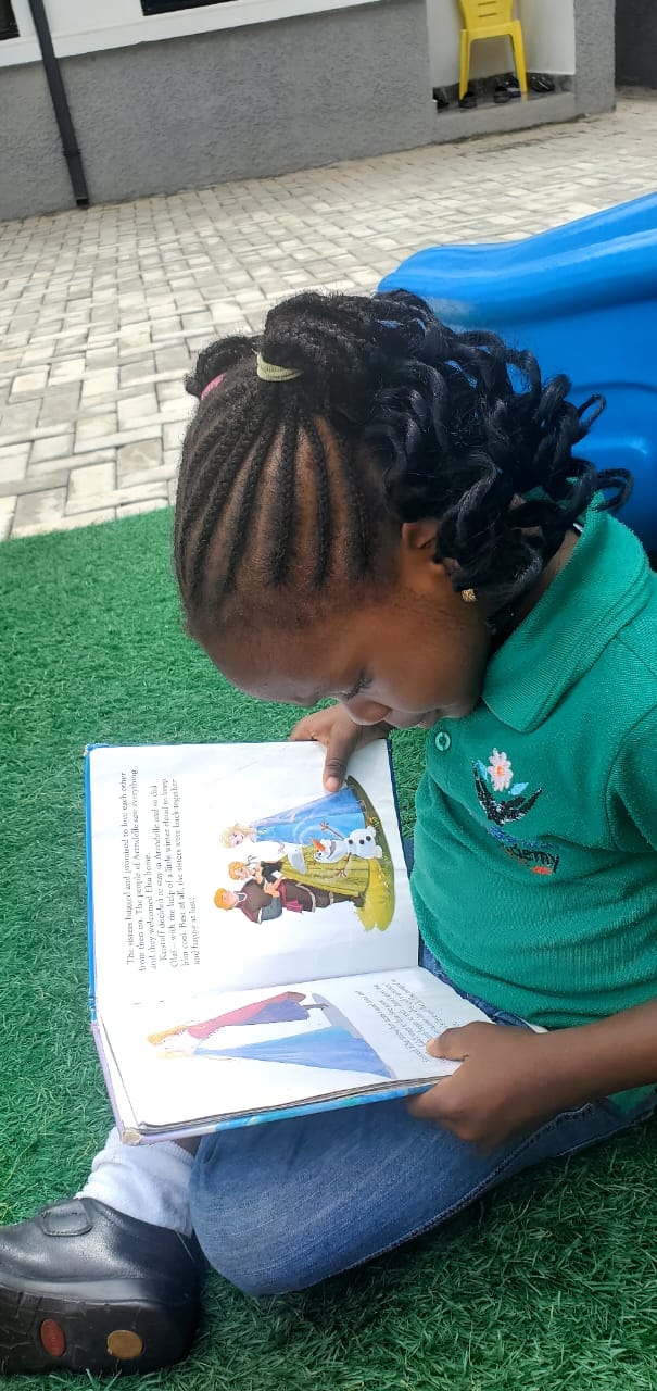 A pupil reading a book outdoors on the turf