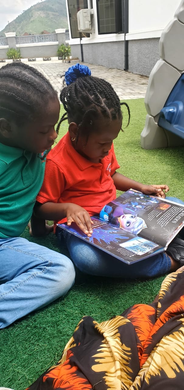 Two Mindbloom Academy pupils sharing a storybook outdoors